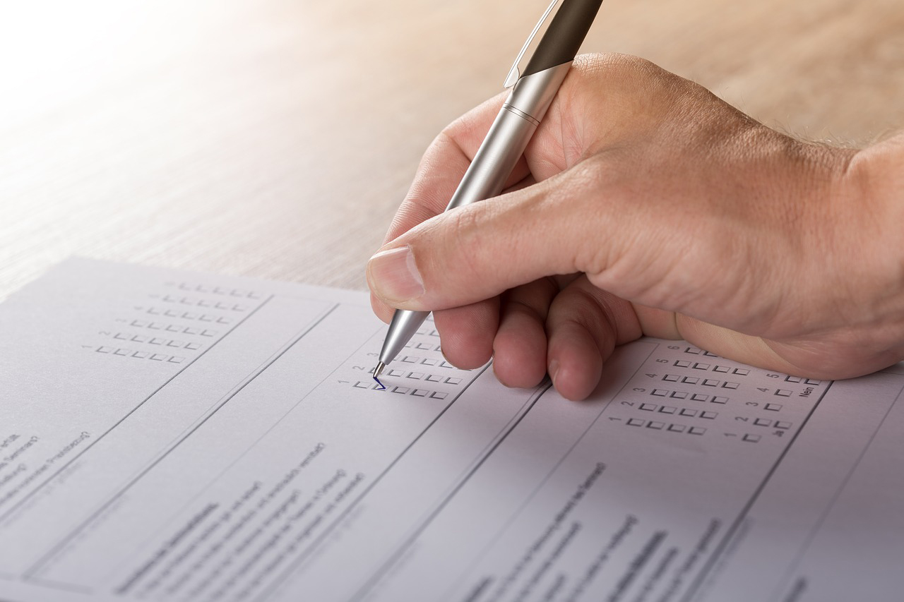  A hand holding a pen is ticking a box next to 'Verified journalists on Twitter platform' on a paper form.