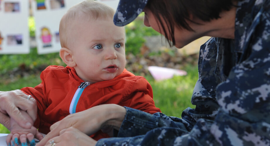 Woman wearing military uniform interacting with toddler