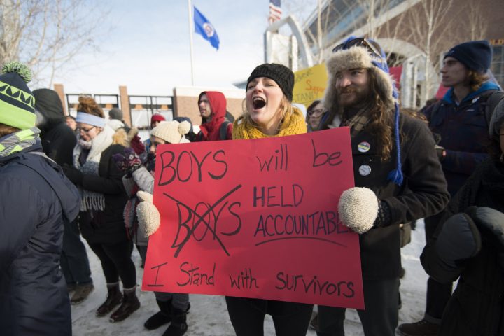 People holding protest signs in support of sexual assault survivors