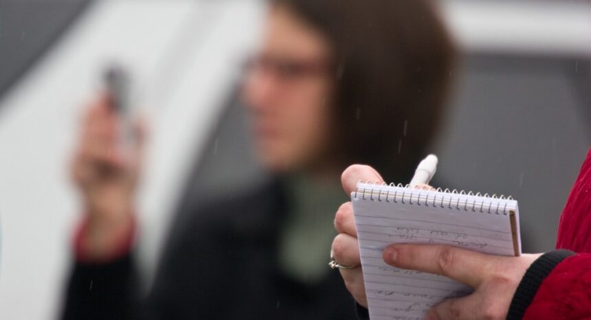 Person writing in reporter's notebook