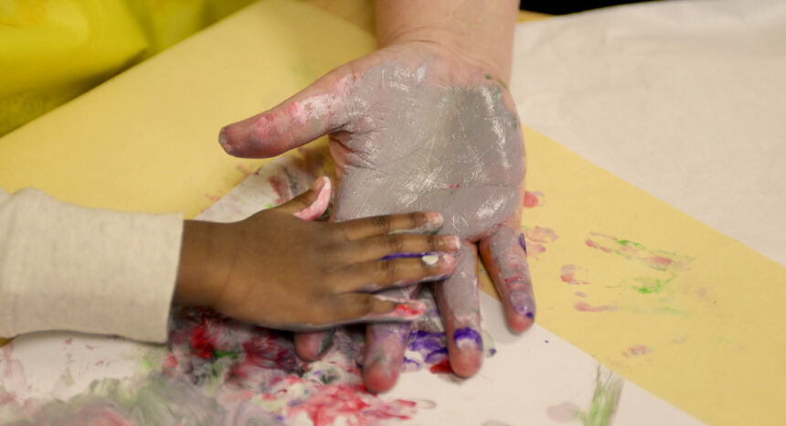 Adult and child hands covered in paint