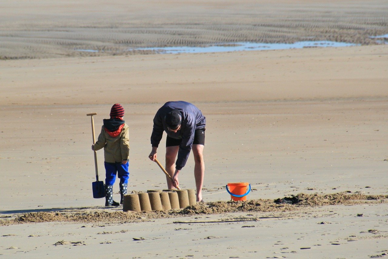 Parent and child make sand castle.