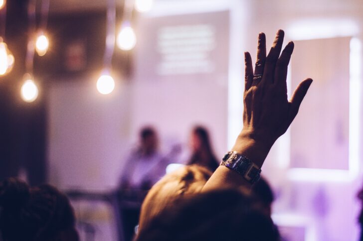 Photo of a raised hand in a conference.