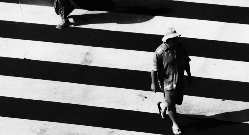 Man on mobile phone cross the road at a pedestrian crossing. Ho