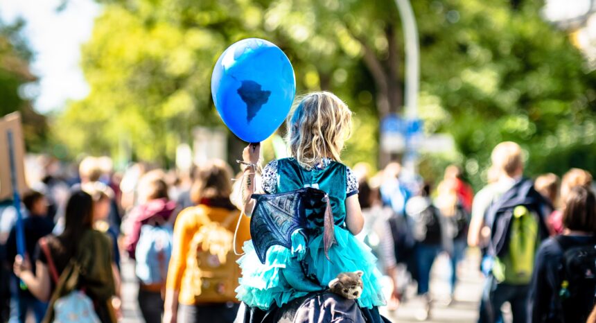 a girl holding a blue balloon with the drawing on continents on it.