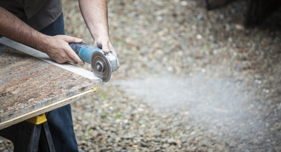 Man cutting granite counter tops outdoors.