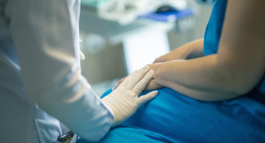 a health care provider with gloved hand touching a patient's arm
