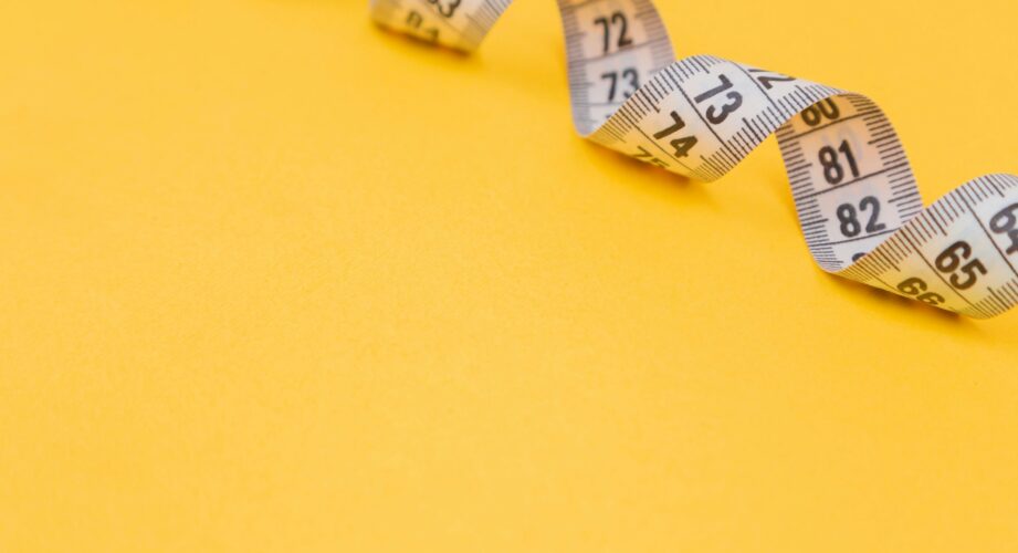 White measuring tape against a yellow background