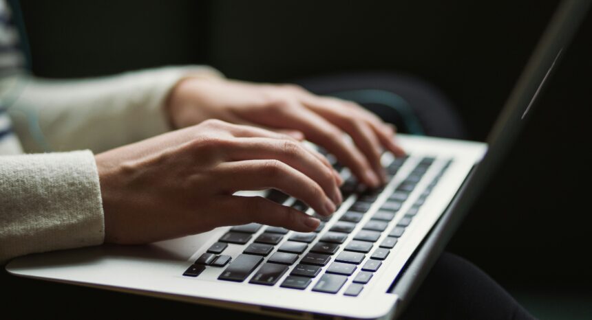 woman's hands typing on a laptop